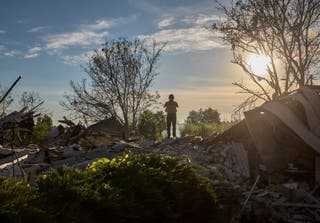 A Ukrainian policeman stands at the site of a glide bomb attack on a private building in Vilkhivka village near Kharkiv